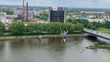 Eine Person hocht hoch oben auf einer Slackline  über der Weser