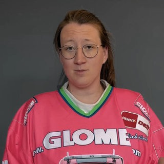 Eine Frau im Eishockey-Trikot schaut in die Kamera