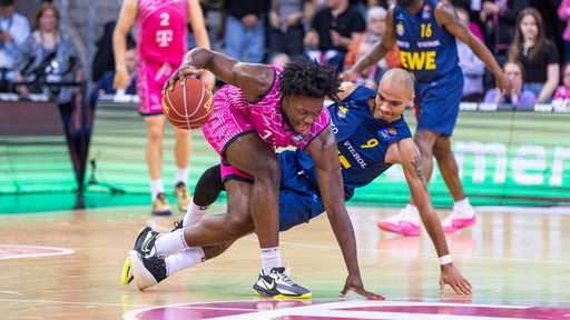 Basketballer der Baskets Oldenburg und der Baskets Bonn mit vollem Körpereinsatz im Kampf um den Ball.