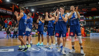 Basketball-Spieler der Eisbären Bremerhaven stehen enttäuscht in blauen Trikots auf dem Parkett und applaudieren ihren Fans nach einer Niederlage.