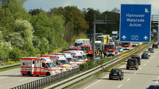 Auf einer Autobahnfahrbahn stehen mehrere Kranken- und Feuerwehrwagen.