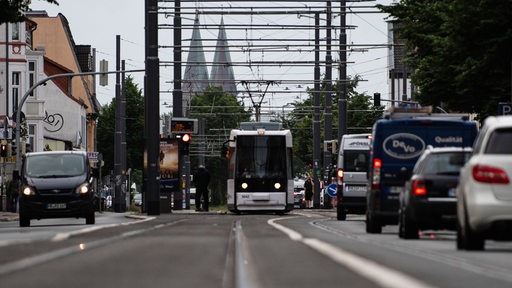 Eine Straßenbahn und Autos fahren morgens im Berufsverkehr durch die Stadt.