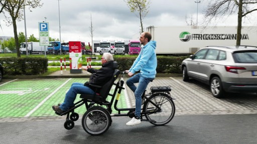 Zwei Menschen auf einem Rollstuhltransport-Rad