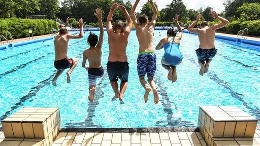 Schüler springen gemeinsam ins Schwimmbecken. (Symbolbild)