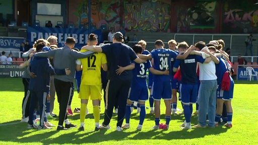 Die Fußballer des Bremer SV stehen Arm in Arm im Kreis und hören Trainer Sebastian Kmiec zu.