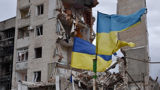 Ukrainische Flaggen wehen vor einem zerstörten Wohnkomplex in Orikhiv.