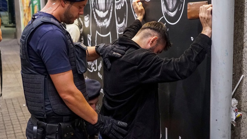 Ein Bundespolizist kontrolliert einen Mann, der Hände an die Wand hält