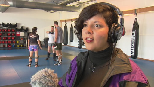 Es ist die Medienkünstlerin und D-Jane Gabi Valdespino in einem Kampfsportstudio zu sehen, in welchem sie Töne sammelt.