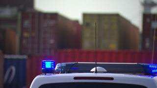 Eine Aufnahme einer Polizeisirene, im Hintergrund sind Container zu sehen.