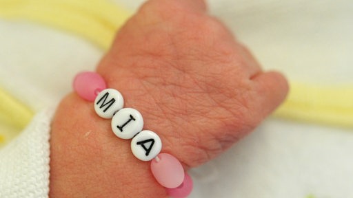 Ein Neugeborenes trägt das Namens-Armband "MIA".