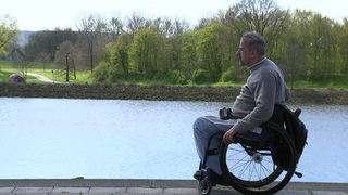 Ein Rollstuhlfahrer fährt an der Weser entlang. 