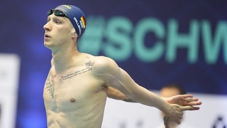 Schwimmstar Florian Wellbrock streckt vor dem Start bei der Deutschen Meisterschaft seine Arme hinter dem Rücken.