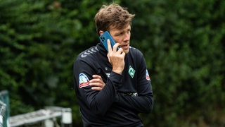 Clemens Fritz telefoniert am Spielfeldrand.