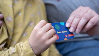 Ein Kind und seine Mutter halten eine Freikarte in den Händen.