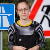 Eine junge Frau steht vor Verkehrsschildern