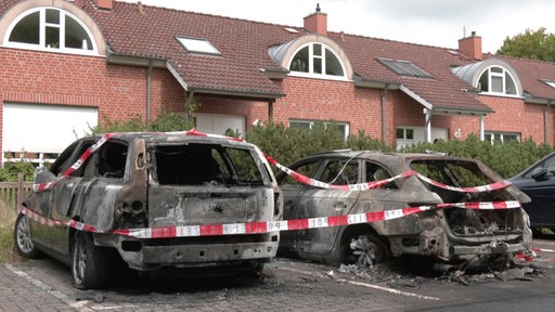 Zwei abgebrannte Autos von Politikern in einer Wohnsiedlung abgesperrt.