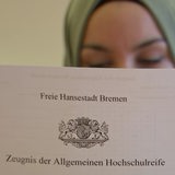 Ein Abiturzeugnis, das von einer Abiturientin gehalten wird.