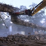 Eine Brücke wird von einem Bagger abgerissen.