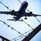 Ein Flugzeug fliegt über einen Stacheldrahtzaun. 