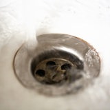 Leitungswasser fließt aus dem Wasserhahn in ein Waschbecken.