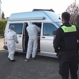 Ermittler der Spurensicherung stehen vor einen Bus der Polizei.