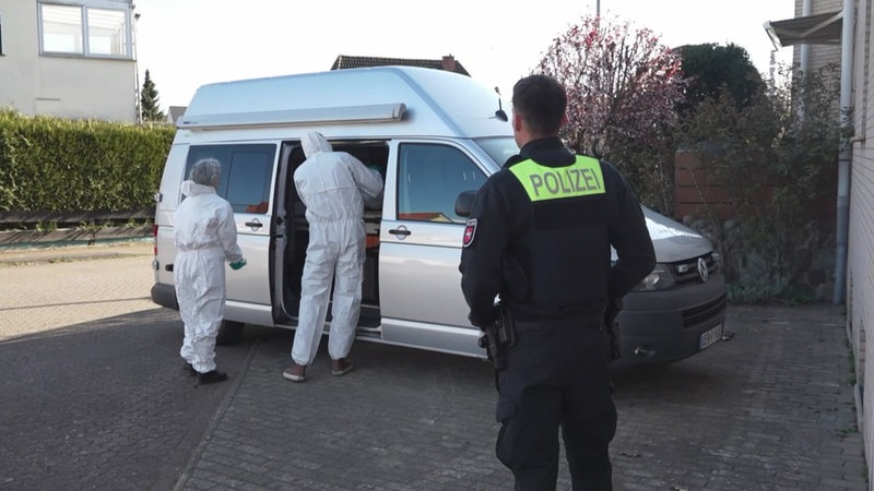 Ermittler der Spurensicherung stehen vor einen Bus der Polizei.