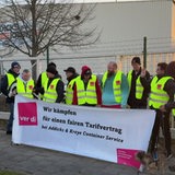 Männer in gelben Warnwesten halten ein Banner mit der Aufschrift "Wir kämpfen für einen fairen Tarifvertrag".