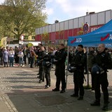 Vor einem Infostand der AfD stehen mehrere Polizisten.
