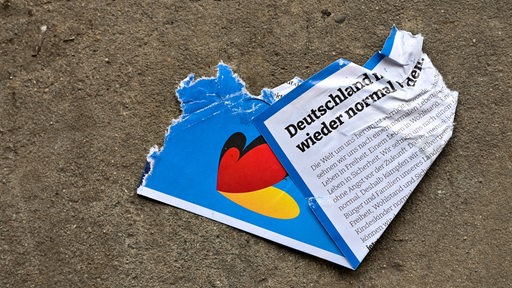 In einer Halle einer Entsorgungsfirma liegt auf dem Fußboden ein zerrissener AfD-Flyer aus dem Bundeswahlkampf.