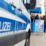 Ein Polizeiauto neben dem Wahlkampfstand der AfD mit einem Plakat der Spitzenkandidatin Alice Weidel