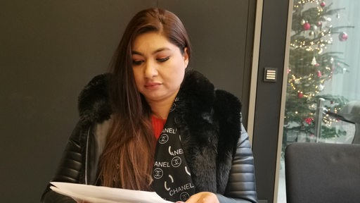 Eine junge Frau blickt auf Dokumente.