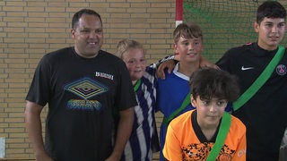 Ex-Werderander Ailton zusammen mit Jugendlichen bei einem Fußballtraining in einer Sporthalle.