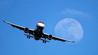 Ein Flugzeug vom Modell Airbus A320 fliegt vor dem Mond