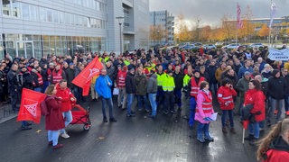 Einige hundert Menschen stehen vor dem Bremer Airbus-Werk während einer Kundgebung der Gewerkschaft IG Metall.