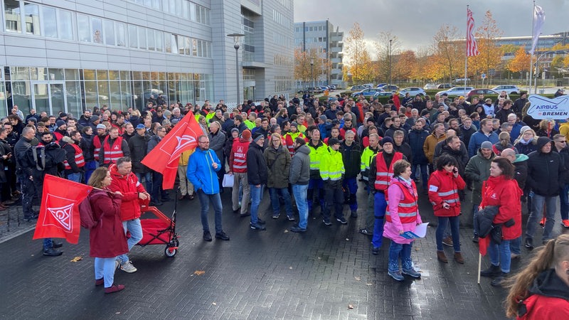 Einige hundert Menschen stehen vor dem Bremer Airbus-Werk während einer Kundgebung der Gewerkschaft IG Metall.
