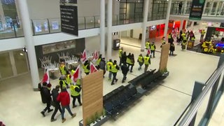 Streikende Mitarbeiter laufen mit geleben Warnwesten durch den Bremer Flughafen