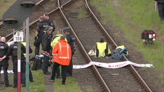 Auf einem Bahngleis sitzt ein Aktivist und blockiert den Verkehr.