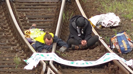 Zwei Männer haben sich an Gleise gekettet.