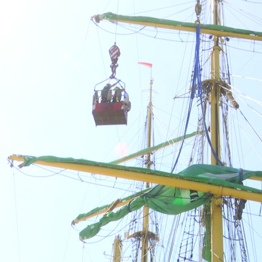 Mehrere Bauarbeiter in einem Krankorb werden an den Mast der "Alexander von Humboldt II" gebracht.