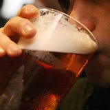 Nahaufnahme: Ein junger Mann trinkt aus einem Bierbecher.