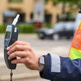 Ein Polizist hält ein Alkoholtestgerät in der Hand.