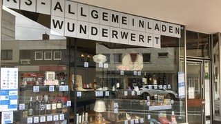Blick auf ein Schaufenster, in dem viele verschiedene Gegenstände, wie Flaschen und Lampen stehen.