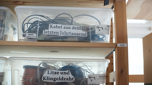 Kabel und Drähte in beschrifteten transparenten Plastikwannen, die in einem Regal stehen
