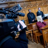 Der Angeklagte sitzt vor Prozessbeginn mit seinen Anwälten im Gerichtssaal. 