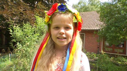 Es ist die 10-jährige Ukrainerin, Anastasia Savenko, mit bunten Blumen und Bändern im Haar zu sehen.