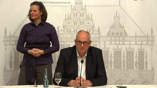 Bürgermeister Andreas Bovenschulte spricht auf einer Pressekonferenz, links neben eine Gebärdendolmetscherin.
