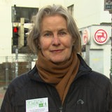 Eine Frau steht vor einer roten Fußgängerampel.