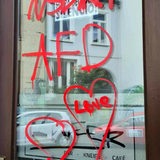 Eine Scheibe ist mit roten Schriftzügen beschmiert. Dort steht unter anderem "AfD" "NSDAP" drauf