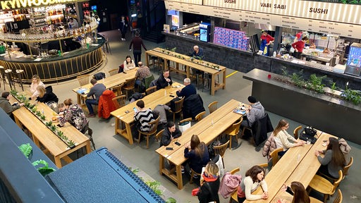 Kiew im Frühjahr 2023: Menschen sitzen beim Essen in einer modernen Markthalle