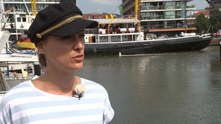 Die plattdeutsche Sängerin Annie Heger in Bremerhaven am Wasser, im Hintergrund sind Boote zu sehen.